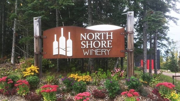 A sign for North Shore Winery surrounded by a landscaped garden with various colorful flowers and shrubs. - Lutsen Log Lodge! Ski, Hike, Golf & Bike (Lutsen)