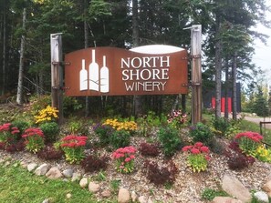 A sign for North Shore Winery surrounded by a landscaped garden with various colorful flowers and shrubs. - Lutsen Log Lodge! Ski, Hike, Golf & Bike (Lutsen)