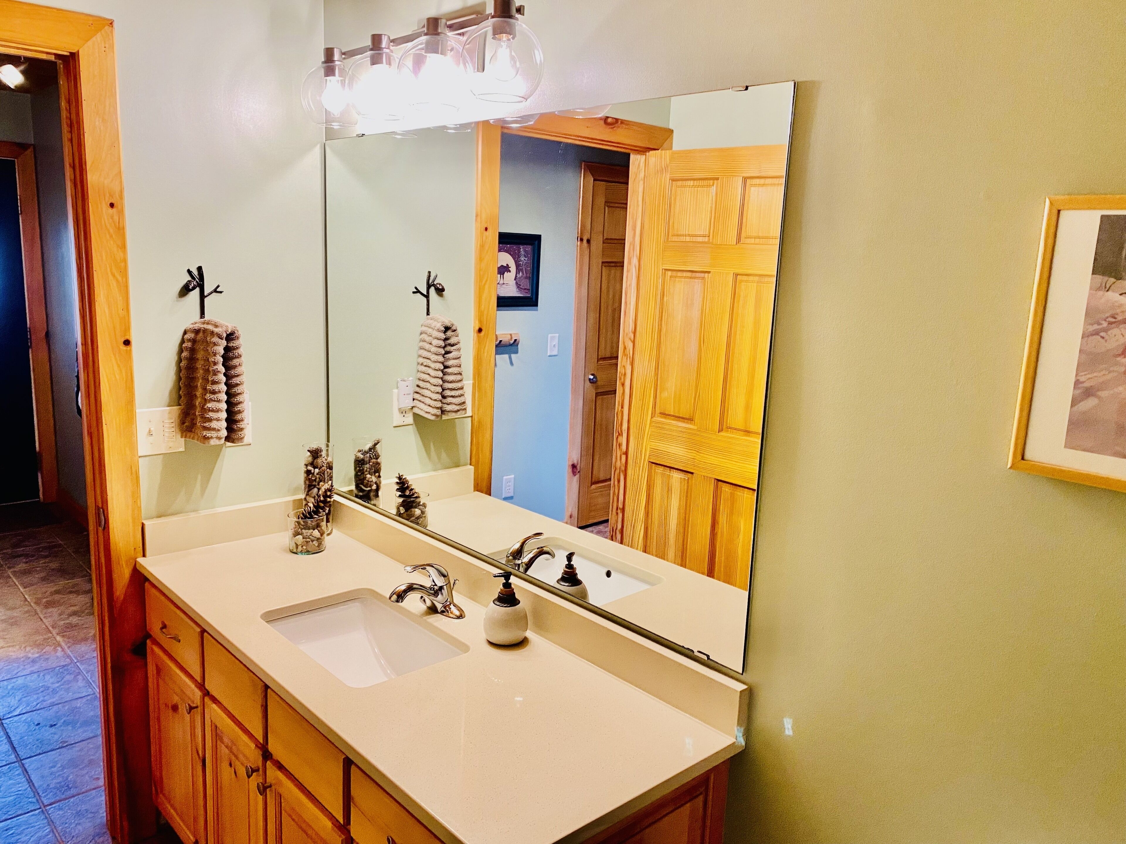 A bathroom with a large mirror, a sink, and wooden cabinets.