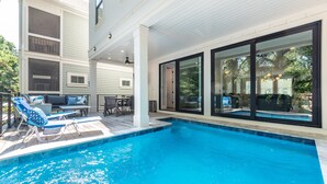 A modern house with a swimming pool, outdoor seating, and large windows. - 113 Custom Sandcastle, Pool, Hot Tub, Kids Suite (Hilton Head Island)