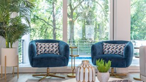 A modern living room with two blue armchairs, a white vase, and a small plant on a round table. - 113 Custom Sandcastle, Pool, Hot Tub, Kids Suite (Hilton Head Island)