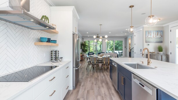 A modern kitchen with white cabinetry, a herringbone tile backsplash, and a central island with seating. - 113 Custom Sandcastle, Pool, Hot Tub, Kids Suite (Hilton Head Island)