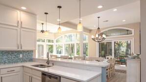 A modern kitchen with white cabinetry, a stainless steel dishwasher, and pendant lighting.