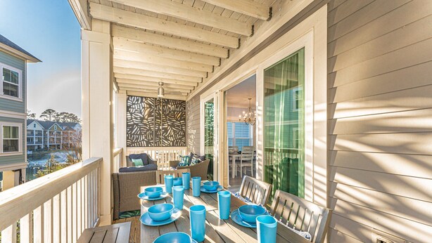 Een houten terras met een eettafel, omringd door stoelen en blauw servies.
