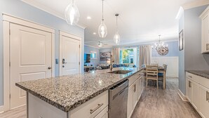 Een moderne keuken met granieten aanrechtbladen, roestvrijstalen apparatuur en hanglampen.