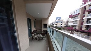 A balcony with a table and chairs, a window with a curtain, and a view of neighboring buildings. - 224, Great apartment a few meters from the beach (Bombas)