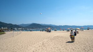 A beach with umbrellas, a tent, and mountains in the background.