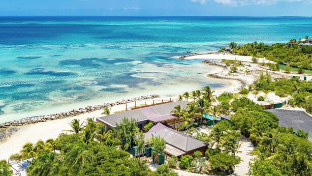 A resort with multiple buildings, a beach, and clear turquoise waters. - Silver Sands Villa Turks and Caicos – 8-Bedroom Luxury Beachfront Villa with Gym & Padel Court (Thompson Cove)