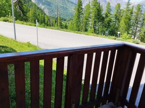 Une terrasse en bois offrant une vue sur une route et des montagnes boisées.