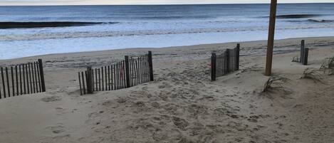 A sandy beach with a wooden fence and a wooden post.
