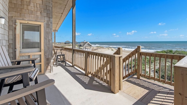 A wooden deck with chairs and a view of the ocean.