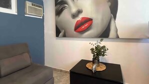 Una sala de estar moderna con una gran obra de arte colgando en la pared, una consola negra con una planta y un sofá gris.