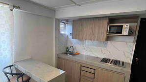 Una cocina compacta con una isla central, taburetes de bar, un microondas y una estufa.