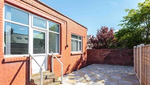 A brick building with large windows and a paved patio area. - Cherry Property - Mulberry Suite (Blackpool)