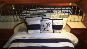 A bed with navy and white striped bedding, a pillow with an anchor design, and a wooden headboard. - Floating Hotel in Paradise !!!! Staniel Cay, Exuma,Bahamas!!! (Staniel Cay)