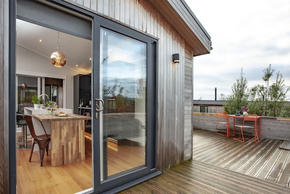 A modern kitchen with a wooden island, a dining area with red chairs, and a view of the outdoors. - Deer Leap, Strawberryfield Park - a lodge that sleeps 2 guests in 1 bedroom (Cheddar)