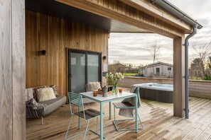 Relax in an outdoor space with a hot tub, sofa, and comfortable seating area.