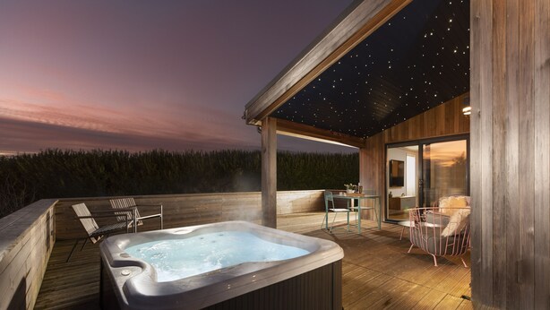A hot tub on a wooden deck with a starry ceiling, overlooking a forested area. - Charterhouse, Strawberryfield Park -  a lodge that sleeps 2 guests  in 1 bedroom (Cheddar)
