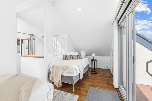 Un dormitorio con cama, mesita de noche y ventana.