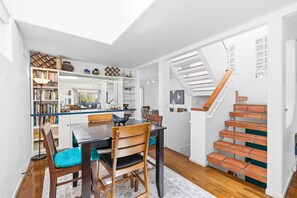 A modern interior with a dining area, bookshelves, and a staircase.
