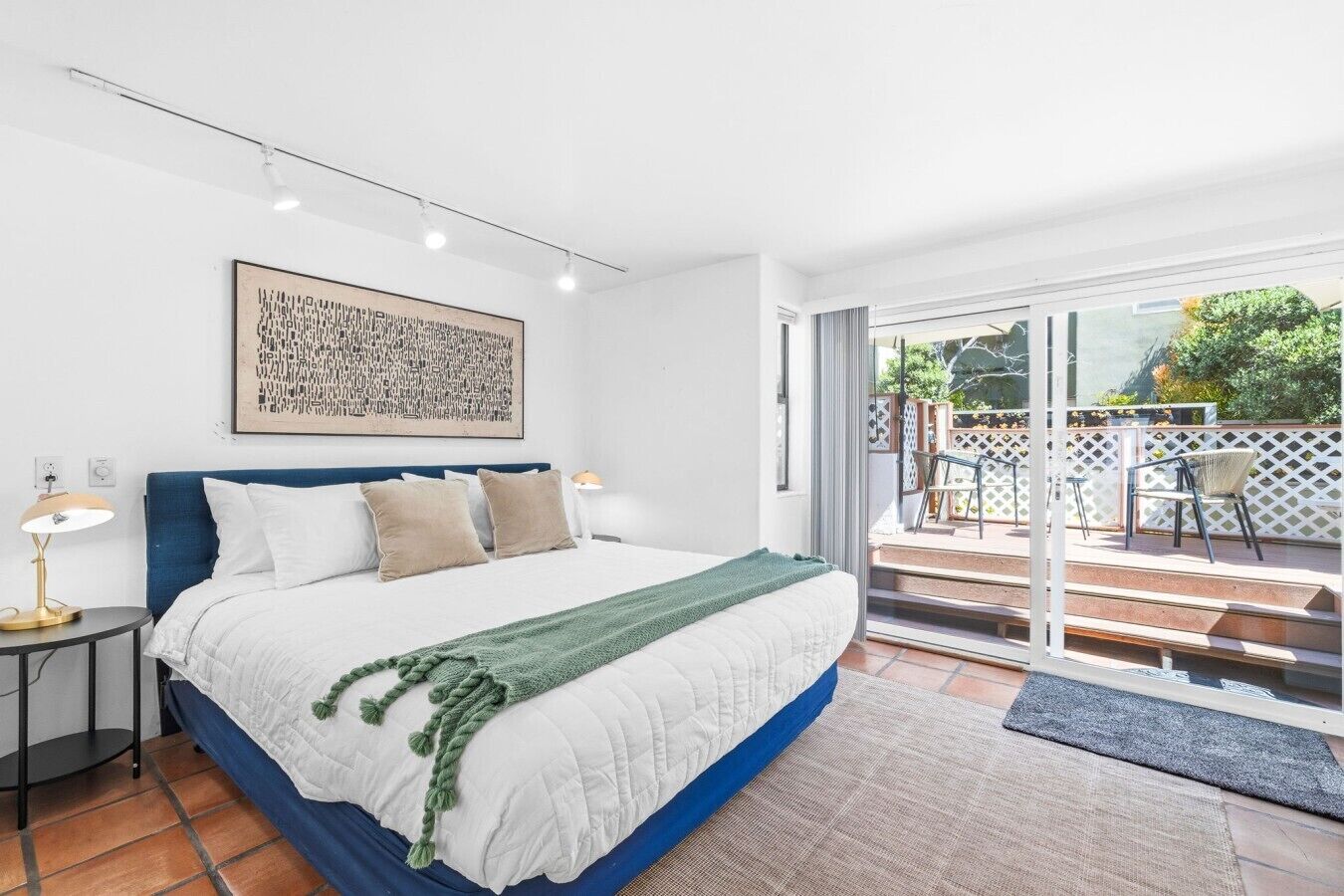 Ein Schlafzimmer mit Bett, Nachttisch und Blick auf eine Terrasse.