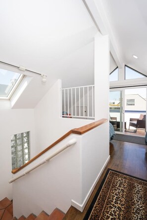 Um interior moderno com uma escada, uma porta de vidro e vista para o exterior.