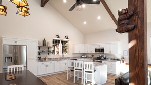 A spacious kitchen with white cabinetry, a large island, and a dining area with chairs. - Half Dome Loft (Yosemite National Park)