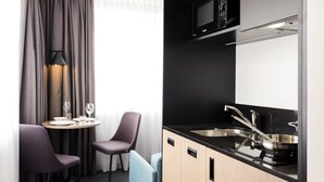 A compact kitchenette with a microwave, sink, and stove. There is a dining area with a table and chairs. - Executive Residency by Best Western Amsterdam Airport (Hoofddorp)