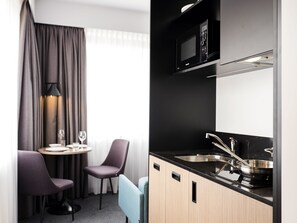 A compact kitchenette with a microwave, sink, and stove. There is a dining area with a table and chairs. - Executive Residency by Best Western Amsterdam Airport (Hoofddorp)