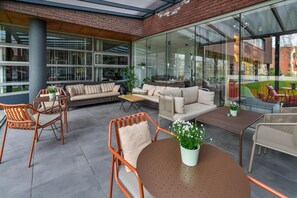 An outdoor seating area with wicker furniture, a sofa, and a table. - Executive Residency by Best Western Amsterdam Airport (Hoofddorp)