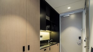 A modern kitchen with a sink, cabinets, and a door with a handle.