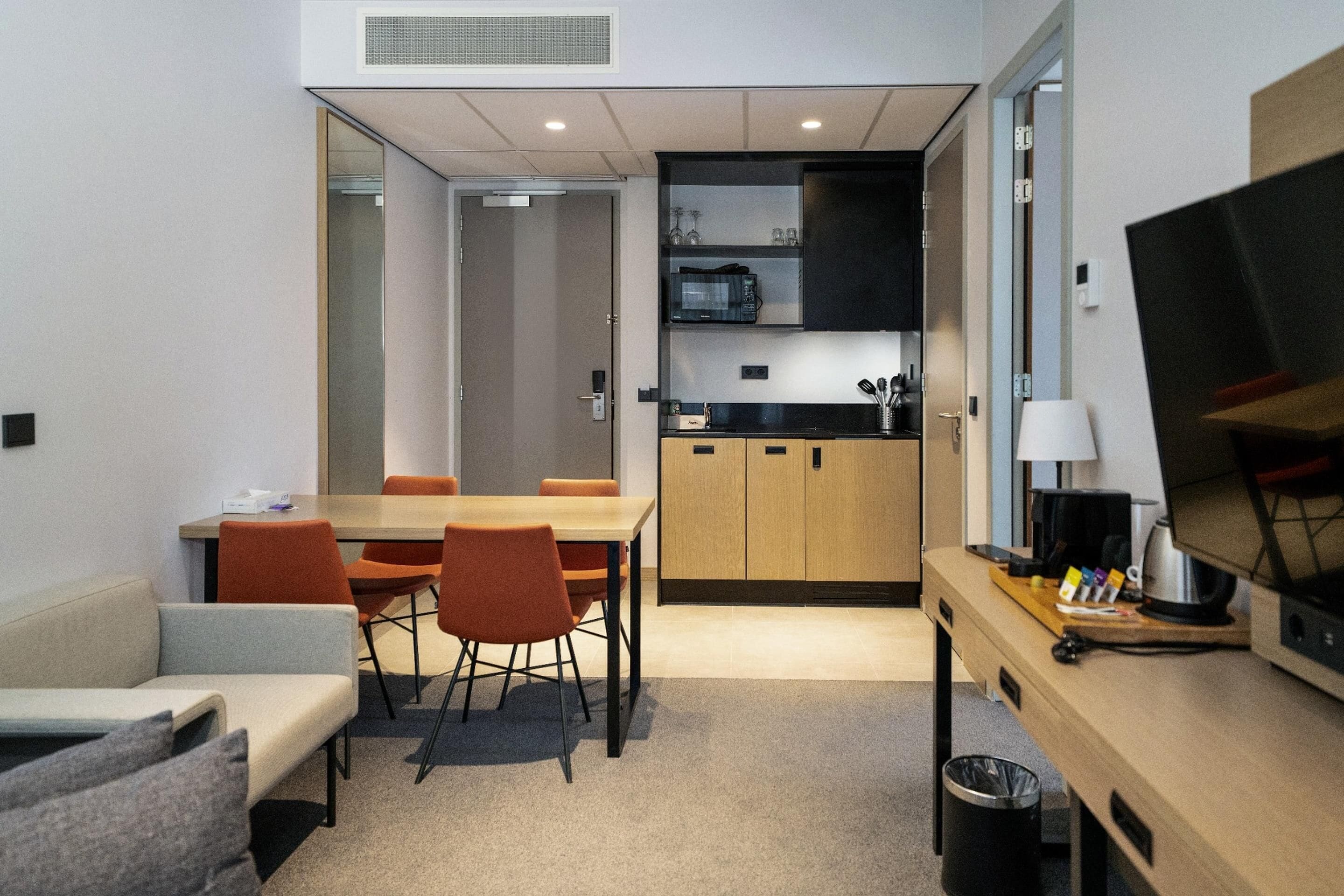Habitación de hotel pequeña con comedor, kitchenette y televisor.