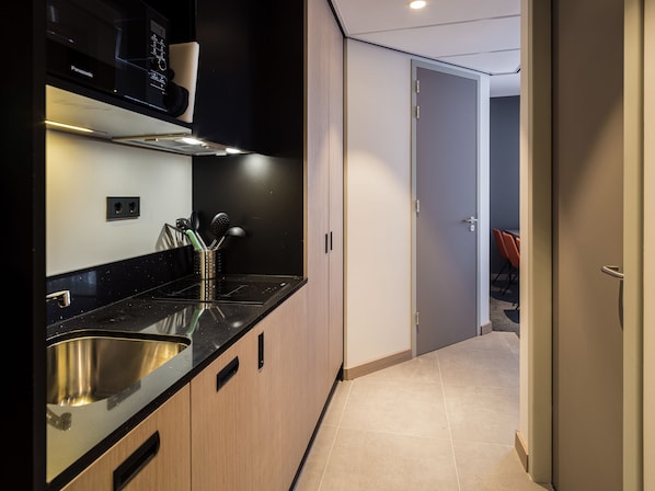 Une cuisine moderne avec un plan de travail noir, un évier en acier inoxydable et des armoires en bois.