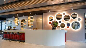 Un área de recepción moderna con bar, asientos y una pared con espejos circulares.