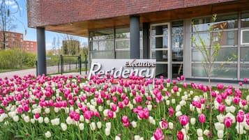 A building with a sign reading 'Executive Residency' and a garden of pink and white tulips in front.