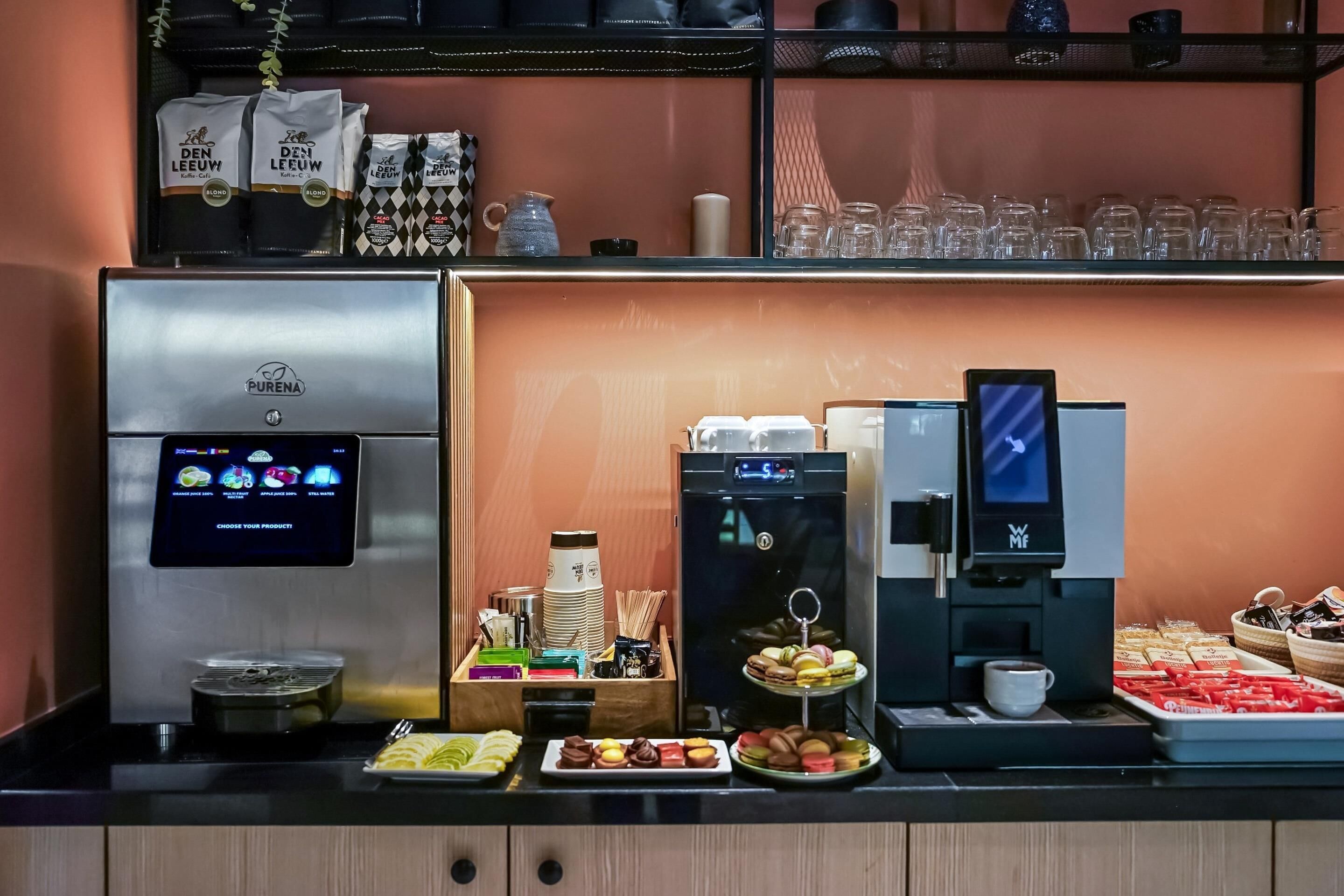 Een automaat met drankjes, inclusief een koffieapparaat, een waterdispenser en een assortiment snacks en gebak.