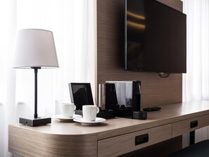 A hotel room with a wooden desk, a flat-screen TV, a lamp, and a coffee maker. - Executive Residency by Best Western Amsterdam Airport (Hoofddorp)