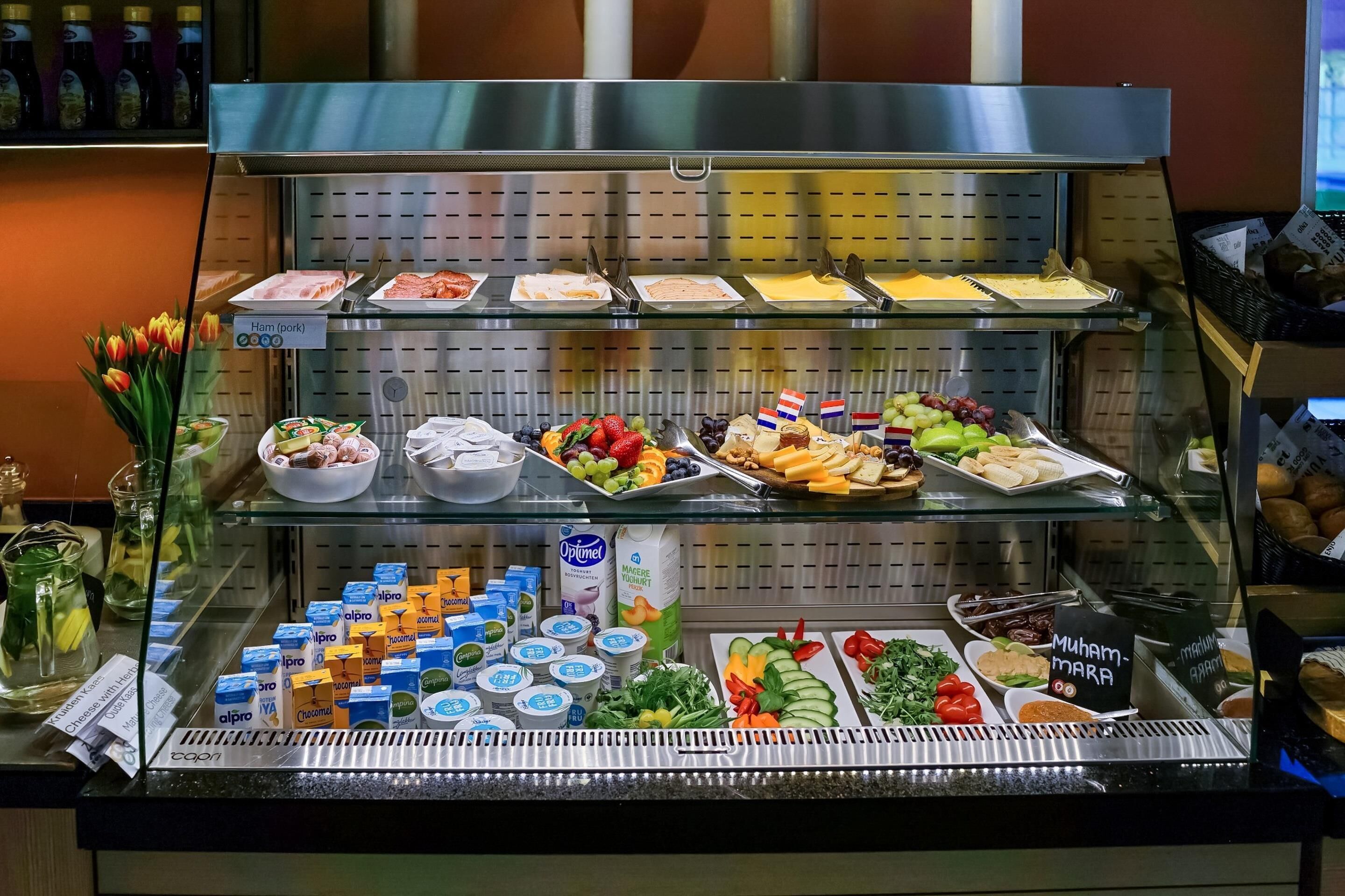 A buffet with various food items including ham, cheese, fruits, and dairy products.