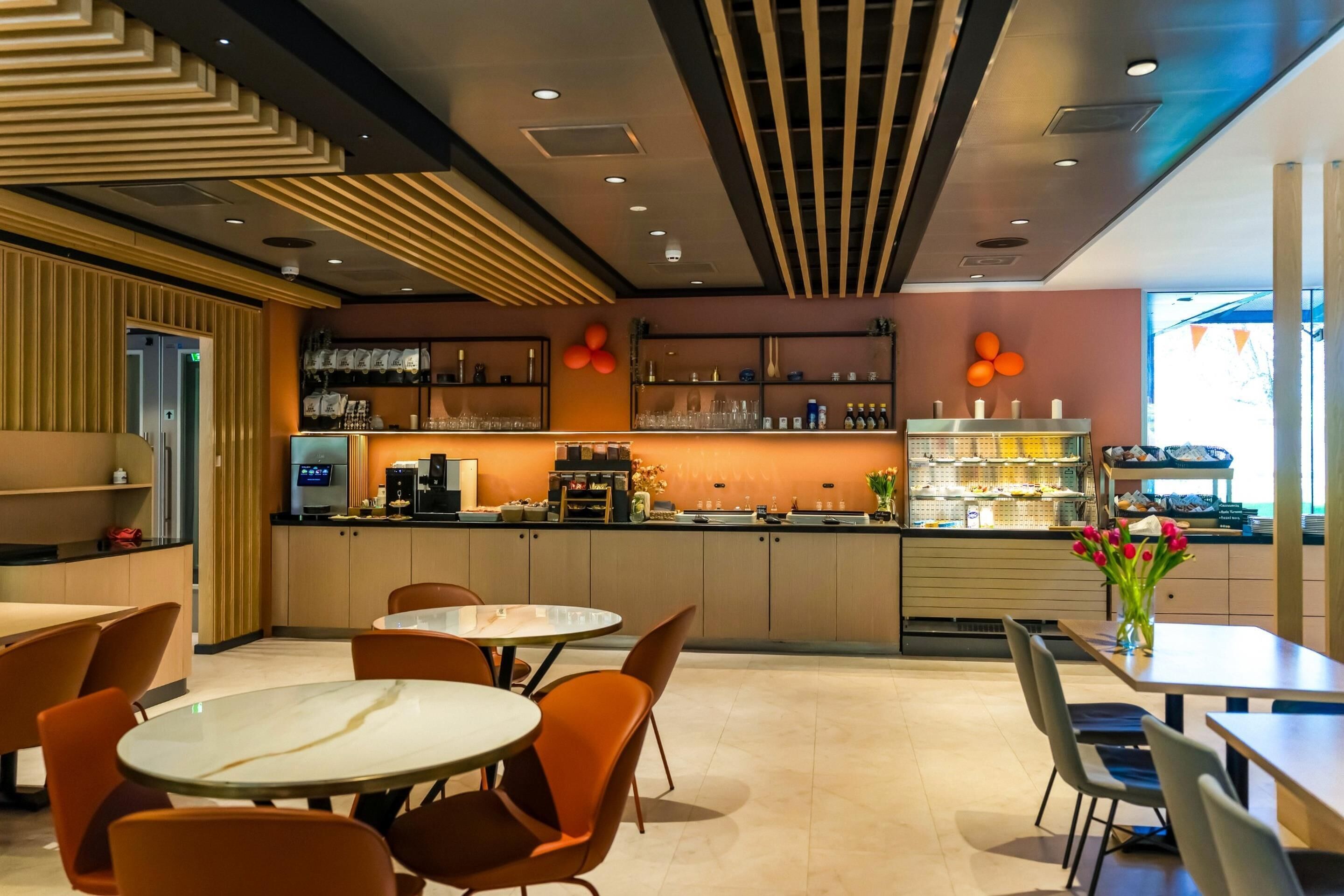 En modern restauranginteriör med en bardisk, sittplatser och ett kök i bakgrunden.