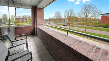 Un balcón con vistas a una calle y un parque.