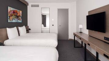 A hotel room with two beds, a TV, a desk, and a painting on the wall.
