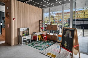 Un intérieur moderne comprenant un espace cuisine, un coin jeux pour enfants et un tableau noir pour les activités artistiques.