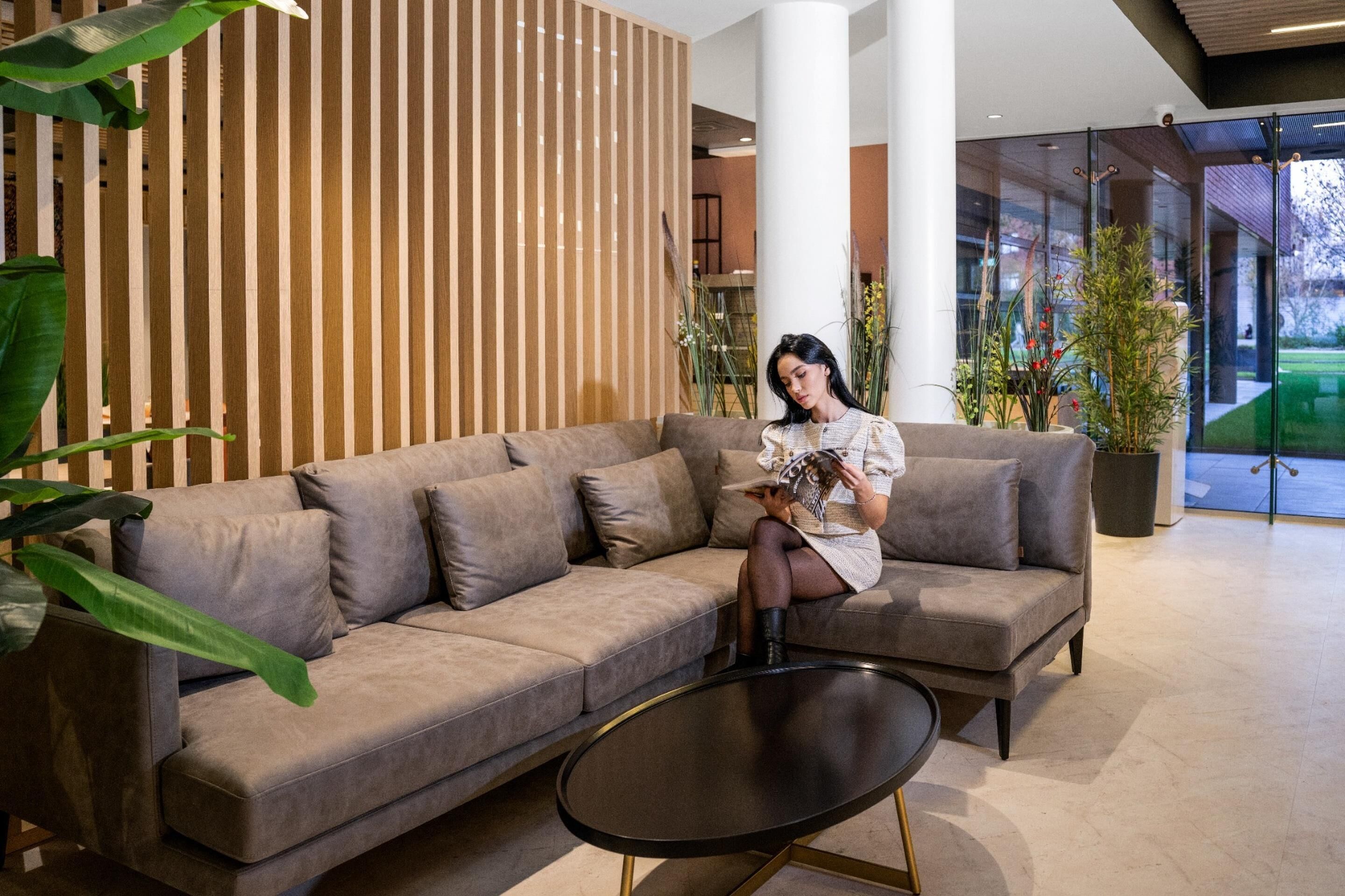 Un interior moderno con un sofá modular, una mesita redonda y plantas de interior.