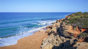 Paesaggio costiero con spiaggia sabbiosa, scogliere rocciose e l'oceano.