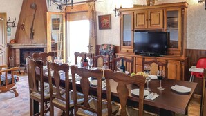 Zona pranzo con arredi in legno, camino e televisione.