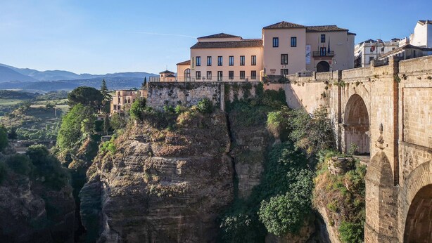 Un edificio storico a più piani, situato su una scogliera con vista su una valle.