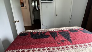 Makuuhuoneessa on sänky, vaatekaappi, televisio ja ovi, joka johtaa toiseen huoneeseen.