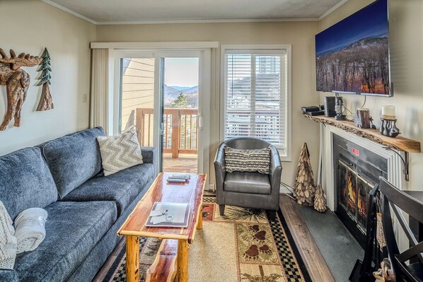 A living room with a sofa, a chair, a fireplace, and a television.
