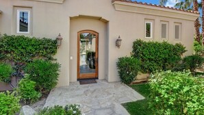 Une maison avec un porche en pierre, une porte en bois et une petite fenêtre ronde située au-dessus de la porte.
