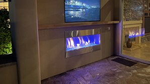 Une cheminée d’extérieur moderne, avec un téléviseur à écran plat fixé au-dessus.